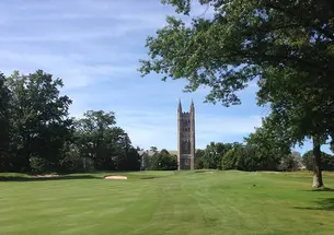 A bell tower is in the background; a golf course is in the foreground.