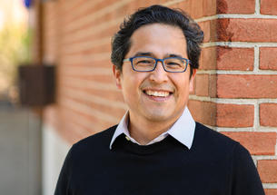Andrés Monroy-Hernández standing in front of a brik wall