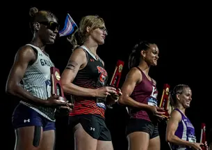 Winning athletes hold their trophies on the awards stand at the end of a track meet.