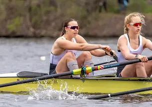 Two women row in a crew boat.