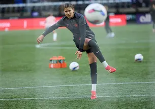 Pietra Tordin follows through on a right-footed shot, with a soccer ball in the air in foreground