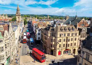 A birds-eye view of Oxford's quaint streets, with a red double-decker bus driving down the middle.
