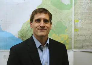 Rupert Elderkin *14 standing in front of a wall of maps