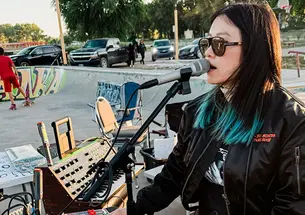 A woman sings into a microphone in a skate park.