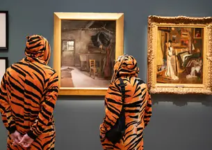 Two people dressed in tiger costumes view art on display during opening night at the Princeton University Art Museum.