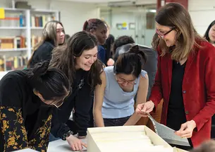 Four women cluster around a table, looking at something on it.