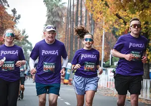 Four people run outdoors in purple T-shirts.