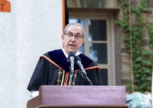 Wearing academic robes, Princeton President Christopher Eisgruber ’83 speaks at a podium.