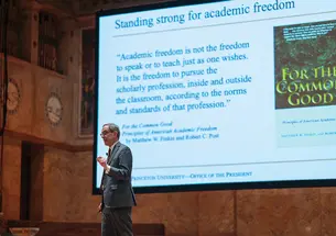 President Eisgruber speaks in front of a screen with a presentation about academic freedom.