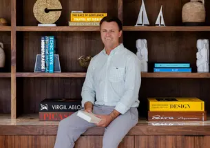 Michael Tibbetts sit on a counter in front of a books shelf 