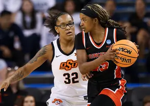 A woman blocks another holding a basketball during a game.