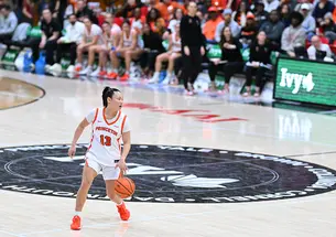 Basketball player Ashley Chea dribbles the ball with her left hand near half court
