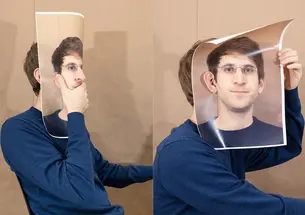 Ben Denzer self portrait holding up a printed piece of paper with his image printed on it and covering his face with it