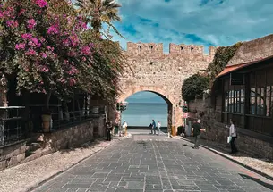 A true in bloom to the side of a brick archway and cobble stone streets.