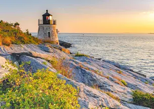 Tiger-Travels_Newport-Rhode-Island_Jennifer-Roosth.jpg A senice view of a rocky ledge leading out to a Castle Hill Lighthouse and a view of the water at sunset.