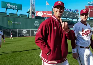 Baseball coach Ryan Forrest holds up index finger while walking on the outfield grass at Fenway Park