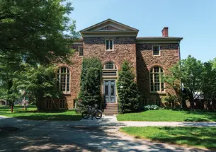 A brick building with crisscrossing pathways out front.
