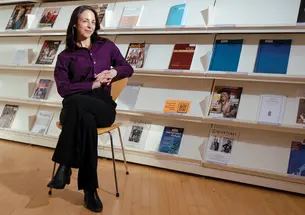 Elizabeth Margulis sitting in a room in front of a row of magazines