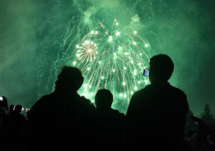 A crowd watches green fireworks.