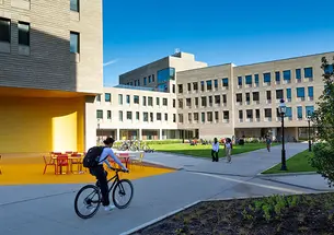 Student riding a bicycle next to dormitories