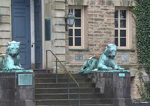 Two bronze tiger statues flank a door on a stone building, Princeton’s Nassau Hall.