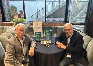 Photo of Bill Rosenblatt and Howie Singer sitting around a table with their book "Key Changes"