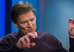 This is a photo of author Michael Lewis ’82 gesturing with his hands while he speaks during a 2014 interview at Reuters about his book “Flash Boys,” about high-frequency trading. 