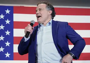 AP_22154784021647.jpg This is a photo of David McCormick speaking into a microphone, with a large American flag in the background.