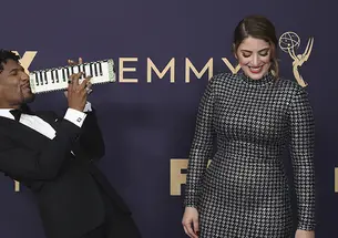 Suleika Jaouad ’10, right, and Jon Batiste arrive at the Emmy Awards on Sept. 22, 2019, in Los Angeles. Batiste plays a melodica while Jaouad laughs.