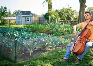 With his eyes shut, Calvin Van Zytveld ’19 plays a cello outdoors, a garden and a shed in the background.