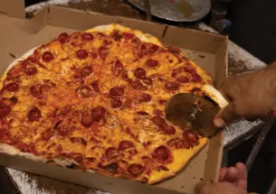 CONTES_pepperoni.png A pizza cutter slices into a pepperoni pizza in a pizza box.