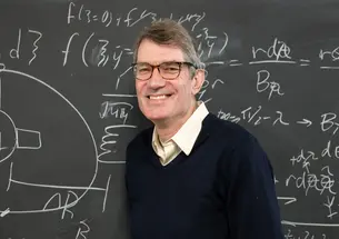 Steve Cowley *85 in front of a chalkboard