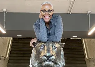 Deborah Saint Phard leans forward over a statue of a tiger.
