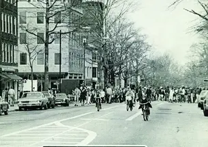 A black-and-white photo on the cover of PAW showing people bicycling down Nassau Street and a sign reading "Road Closed."