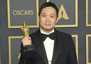 Director Ryusuke Hamaguchi holds an Oscar statue.