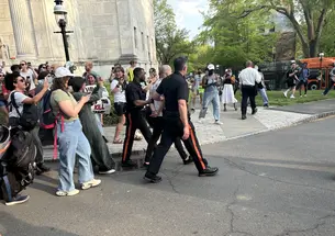 Two protesters are arrested by Public Safety officers and loaded onto a bus during the occupation of Clio Hall on April 29.