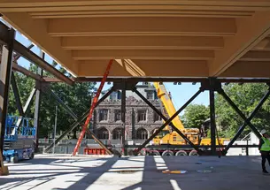 A Gothic Princeton building is visible through the framed-out construction of the art museum. A large piece of construction equipment is in the middle.