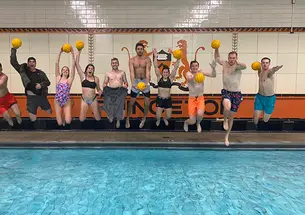 Holding yellow water polo balls, Princeton’s intramural water polo team jumps into the pool.