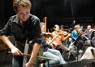 Sean Friar GS bows a car fender during a rehearsal of his “Clunker Concerto.”