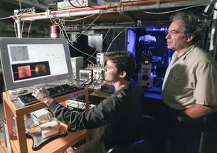 Physics professor Robert Austin, right, and graduate ­student Guillaume Lambert observe prostate cancer cells growing on chips of silicon and silicon-based plastic.