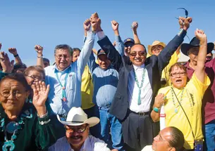 Rex Lee Jim ’86, center, joins hands with Navajo Nation presidential candidate Ben Shelly at a campaign stop in September at the Southwest Navajo Fair in Dilkon, Ariz.