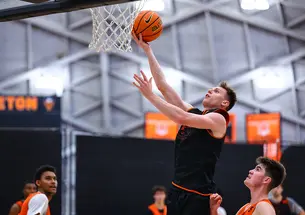 A man lifts a ball nearly to the rim of the basket.
