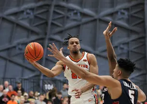 Tosan Evbuomwan ’23 palms the ball as an opposing player tries to block him.