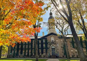 Nassau Hall in the fall, with trees turning yellow, red and orange.