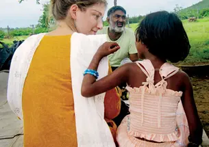 Shaina Watrous ’14, director of a documentary about Ajeet Singh, center, listens to a child in Varanasi, India.
