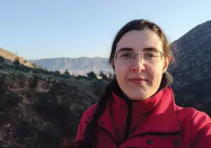 Elizabeth Tsurkov standing by a mountain landscape