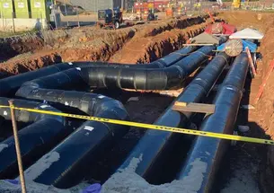 This is a photo of the thermal piping installed near Jadwin Gym — four big black pipes down in a dug-out area of reddish dirt..