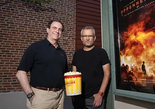 Mark F. Bernstein ’83, left, and Alexander Glaser with popcorn and the Oppenheimer movie poster.