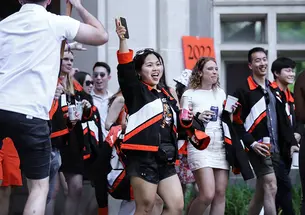 A woman raises her cell phone in the air; a "2022" sign is behind her.