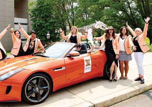 Photo of alumni with orange sports car